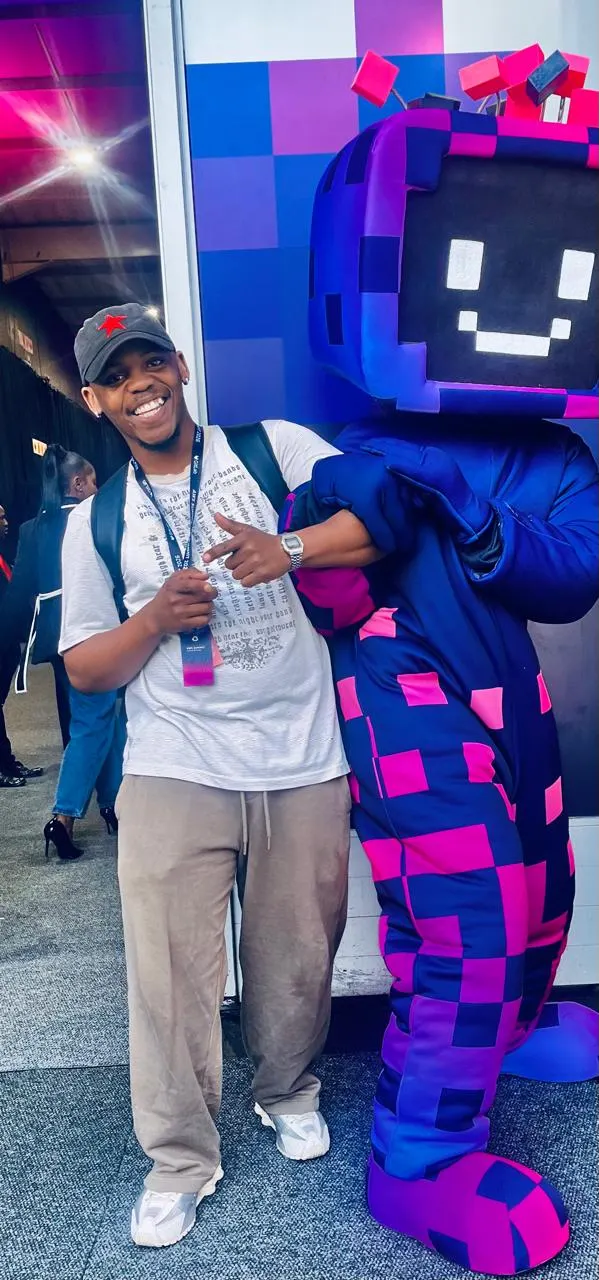 Maredi Manyama smiling beside the AWS mascot at the AWS Summit